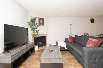 a living room with a gray couch and a fireplace at 2BR Hollywood Apt with Rooftop Pool & Stunning Views in Los Angeles