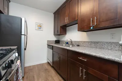 a kitchen with wooden cabinets and a stainless steel refrigerator at 2BR Hollywood Apt with Rooftop Pool & Stunning Views in Los Angeles