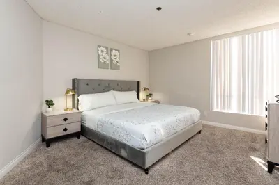 a white bedroom with a bed and a window at 2BR Hollywood Apt with Rooftop Pool & Stunning Views in Los Angeles