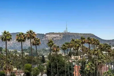 a hollywood sign on top of a mountain with palm trees at Modern Escape in Hollywood with Rooftop & City Views in Los Angeles