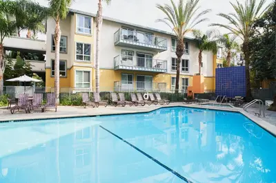 a swimming pool in front of a building with palm trees at The Amethyst Retreat Ocean Marina Panoramic View in Los Angeles