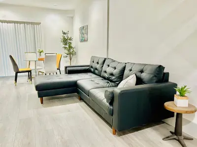 a living room with a black couch and a table at Newly Built Modern Central 2B On Sherman with Free Parking in North Sherman Way