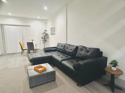 a living room with a black couch and a table at Newly Built Modern Central 2B On Sherman with Free Parking in North Sherman Way