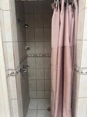 a shower with a pink shower curtain in a bathroom at Haystack Motel in Long Beach