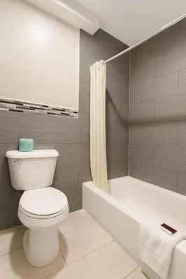 a bathroom with a white toilet and a bath tub at Casa Blanca Hotel - Corona in Corona