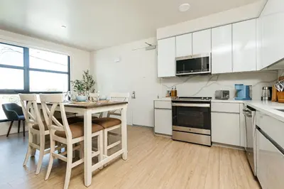 a kitchen with white cabinets and a table and chairs at Stunning 2BR apartment steps from Santa Monica pier in Los Angeles