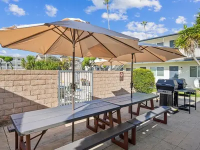 two picnic tables with an umbrella and a grill at Beautiful 2 Bed Beach Condo #104 in Carpinteria