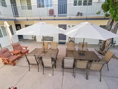 an outdoor patio with tables and chairs and umbrellas at Beautiful 2 Bed Beach Condo #104 in Carpinteria