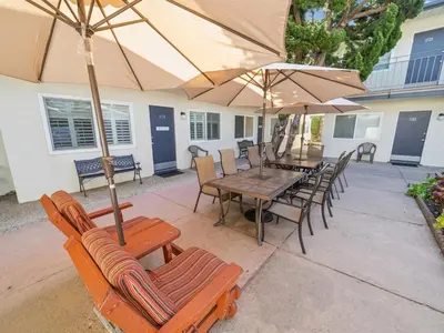 a patio with a table and chairs and umbrellas at Beautiful 2 Bed Beach Condo #104 in Carpinteria