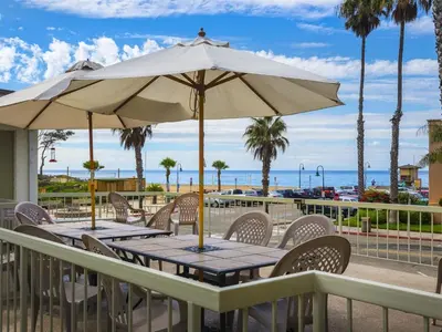 a wooden table with an umbrella on the beach at Beautiful 2 Bed Beach Getaway #115 condo in Carpinteria