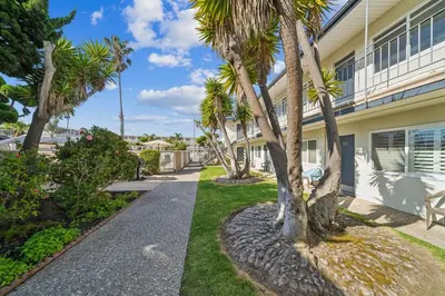 a walkway in front of a building with palm trees at Beautiful 1 Bed Beach Condo #122 in Carpinteria