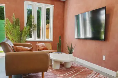 a living room with a couch and a tv on a wall at La Tierra House 15 Min to Beach Movie Lounge in Hawthorne