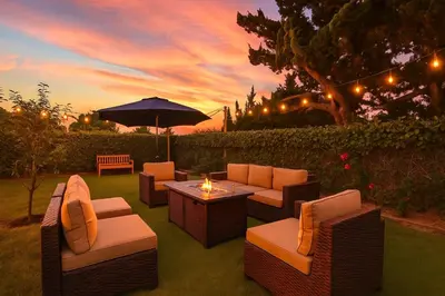 a patio with couches and a table with an umbrella at La Tierra House 15 Min to Beach Movie Lounge in Hawthorne