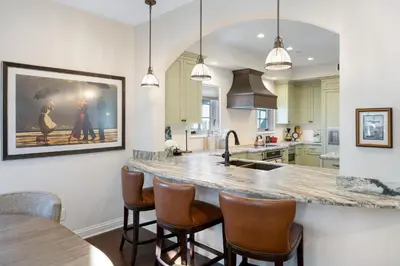 a kitchen with a large island with bar stools at Seventh Shore Stylish Seal Beach Home w Elevator Fireplace Bold Design in Seal Beach