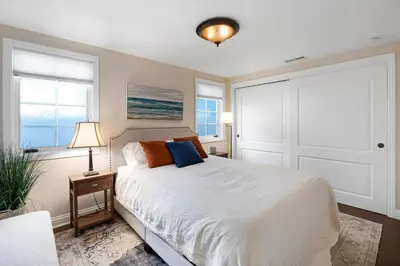 a bedroom with a white bed and two windows at Seventh Shore Stylish Seal Beach Home w Elevator Fireplace Bold Design in Seal Beach