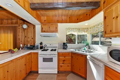 a kitchen with wooden cabinets and a white stove top oven at Acorn Acres - Lake Views for 8 in Lake Arrowhead