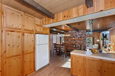 a kitchen and dining room with wooden walls and a white refrigerator at Acorn Acres - Lake Views for 8 in Lake Arrowhead