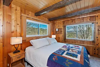 a bedroom with a bed in a wooden cabin at Acorn Acres - Lake Views for 8 in Lake Arrowhead