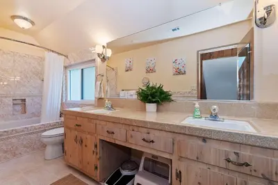 a bathroom with a sink and a toilet and a mirror at Acorn Acres - Lake Views for 8 in Lake Arrowhead