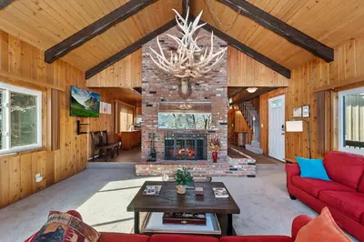 a living room with a fireplace and a red couch at Acorn Acres - Lake Views for 8 in Lake Arrowhead