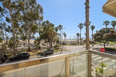 a balcony view of a street with palm trees and cars at The Andalusite - Oceanfront Steps from the Sand in Los Angeles