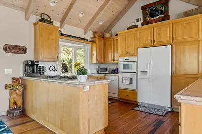 a kitchen with wooden cabinets and a white refrigerator at Bearfoot Lodge near Hiking & Skiing in Lake Arrowhead