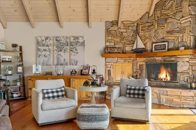 a living room with two chairs and a stone fireplace at Bearfoot Lodge near Hiking & Skiing in Lake Arrowhead