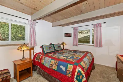 a bedroom with a bed and two windows at Bow N Arrow Lodge For 8 in Lake Arrowhead