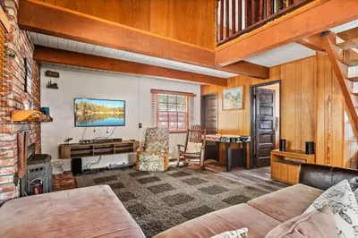 a living room with a couch and a desk and a television at Happy Bear Cabin - Hike Bike & More in Big Bear Lake