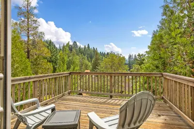 two chairs and a table on a wooden deck at Our Secret Getaway - Two Spacious Living Areas in Lake Arrowhead