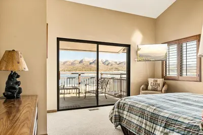 a bedroom with a bed and a balcony with a view at The Adler's Nest - Lakefront with Pool Spa and Summer Dock in Big Bear Lake