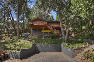 a house in the woods with a staircase leading to it at The Lazy Bear Cabin - For 6 in Crestline