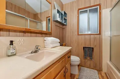 a bathroom with a sink and a toilet and a mirror at The Lazy Bear Cabin - For 6 in Crestline