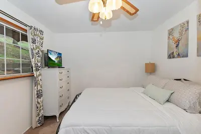 a white bedroom with a bed and a window at The Lazy Bear Cabin - For 6 in Crestline