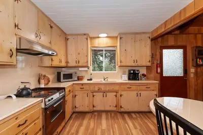a kitchen with wooden cabinets and a stove top oven at The Lazy Bear Cabin - For 6 in Crestline