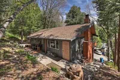 a small house in the middle of a forest at The Lazy Bear Cabin - For 6 in Crestline