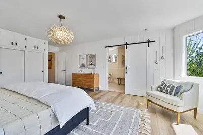 a white bedroom with a bed and a chair at The Lilypad - 2 Master Bedrooms & Game Room in Lake Arrowhead