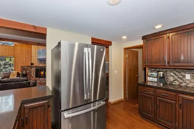 a kitchen with a stainless steel refrigerator and wooden cabinets at Tres Patos - Lakefront Stay for 8 in Green Valley Lake