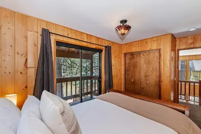 a bedroom with a bed and a large window at Tres Patos - Lakefront Stay for 8 in Green Valley Lake
