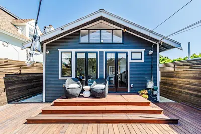 a blue house with two chairs on a wooden deck at Venice 2BR - Ocean Walk with Stunning Outdoor Space! in Los Angeles