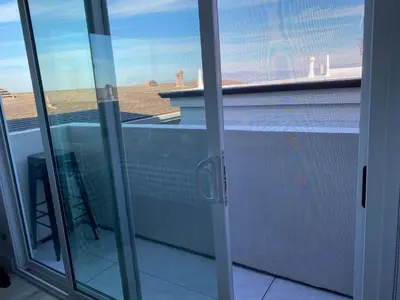 a sliding glass door with a view of a balcony at MB Modern Sand Section Sea View in Manhattan Beach