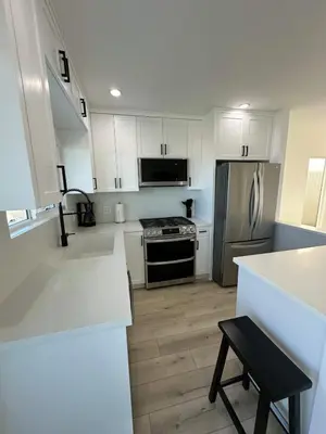 a kitchen with white cabinets and a stainless steel refrigerator at Manhattan Beach Modern Panoramic Sea View in Manhattan Beach