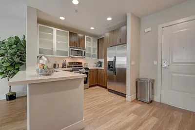 a kitchen with stainless steel appliances and wooden cabinets at Sexy One Bedroom Apartment - Pool View & Parking in Los Angeles