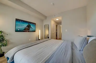 a bedroom with a large bed with a tv on the wall at Sexy One Bedroom Apartment - Pool View & Parking in Los Angeles