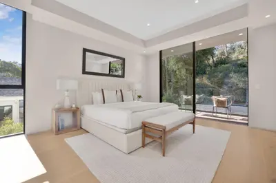 a bedroom with a white bed and large windows at Hutton Villa in Los Angeles
