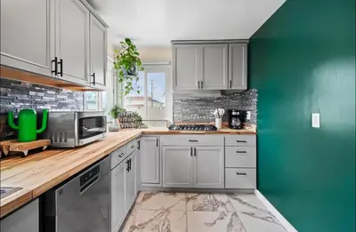 a kitchen with white cabinets and a green wall at Twilight Terrace - Telescope - 15 Min to Beach in Hawthorne
