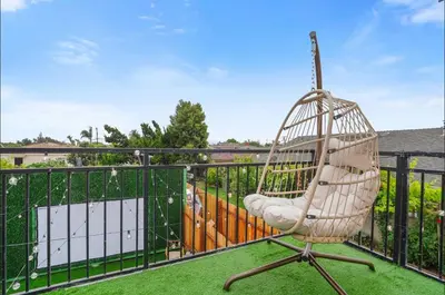 a rattan chair sitting on a balcony at Twilight Terrace - Telescope - 15 Min to Beach in Hawthorne