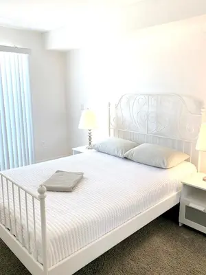 a bedroom with a white bed with white sheets and pillows at Western and Santa Monica in Los Angeles
