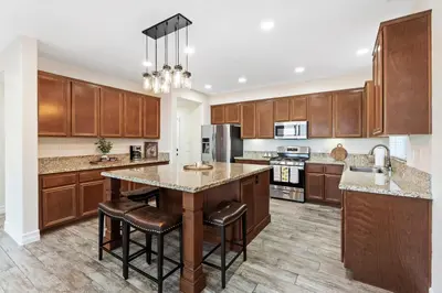 a kitchen with wooden cabinets and a large island with bar stools at Desert Family Oasis 4BR Near Trails Attractions in Palmdale