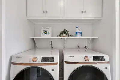 a laundry room with two washing machines and white cabinets at Cascade Cove - Heated Pool Spa - Billiards and Lounge in Long Beach